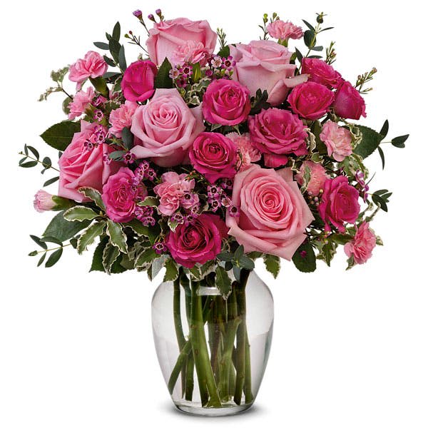 Pink roses and carnations arranged in a clear glass vase
