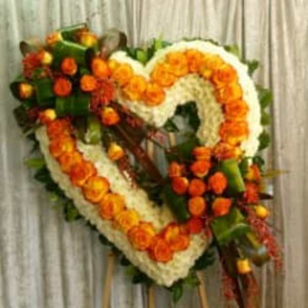 Heart-shaped floral wreath with orange and white flowers on an easel