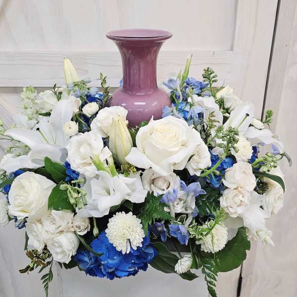 White and blue floral arrangement around a purple vase