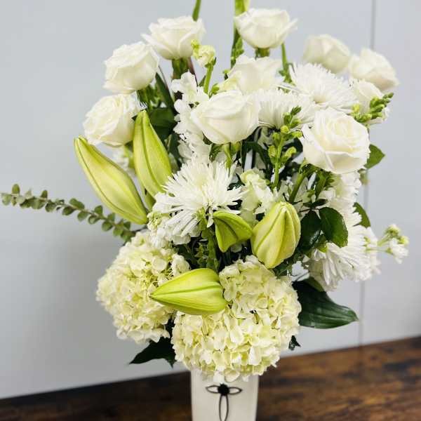 White floral arrangement with roses, lilies, and hydrangeas in a white vase