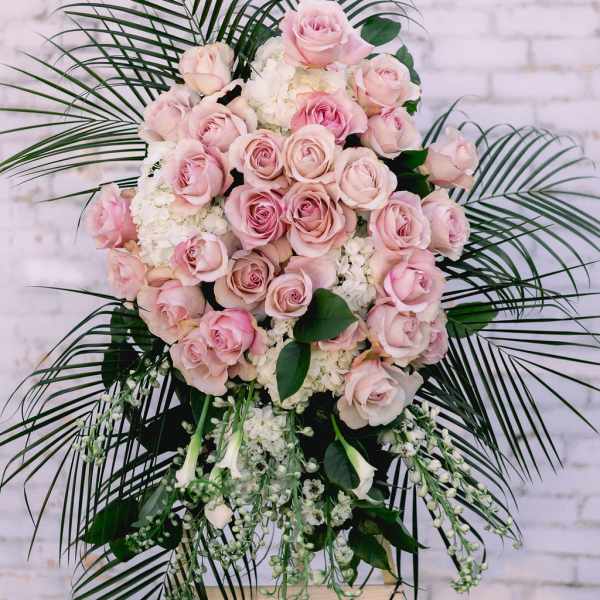 Pink rose standing spray with white flowers and palm fronds