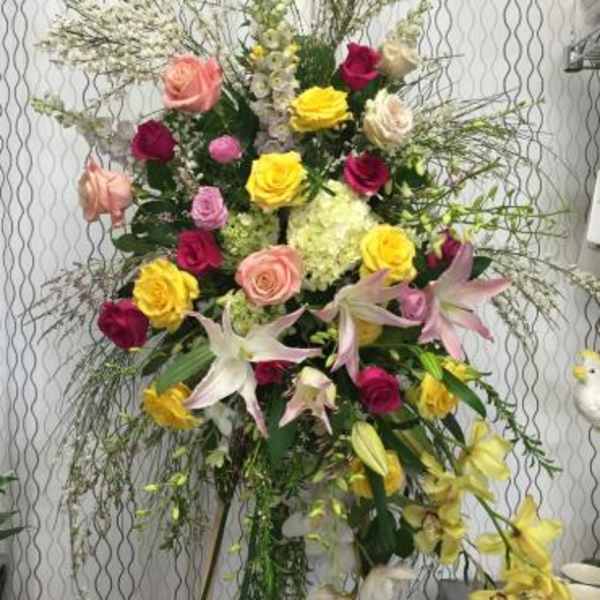 Tall floral spray with roses and lilies in pink, yellow, and white