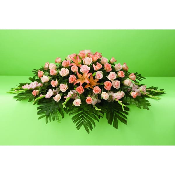 Low floral arrangement of pink roses and lilies on palm leaves
