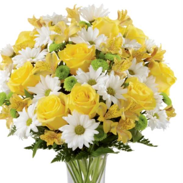 Yellow roses and white daisies arranged in a clear glass vase