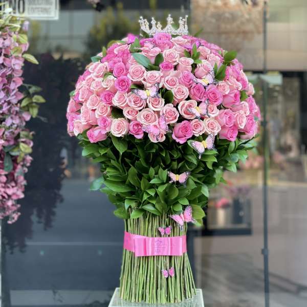 Large bouquet of pink roses with butterflies and a crown topper