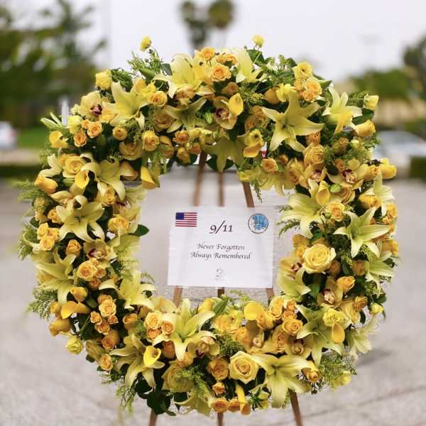 Yellow floral wreath on an easel with a 9/11 remembrance sign