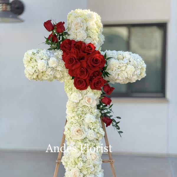 Cross-shaped floral tribute with red and white roses on an easel