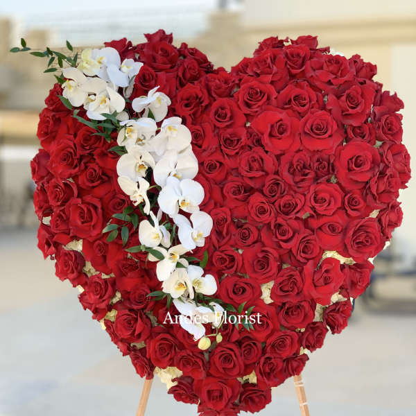 Heart-shaped red rose arrangement with white orchids on an easel