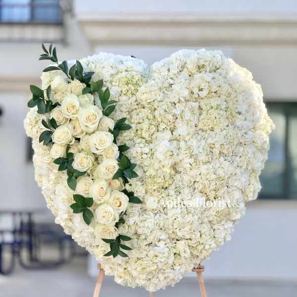 Heart-shaped white floral arrangement with cream roses and greenery