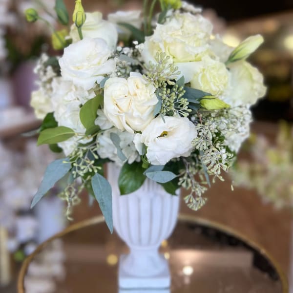 White floral arrangement in a white pedestal vase