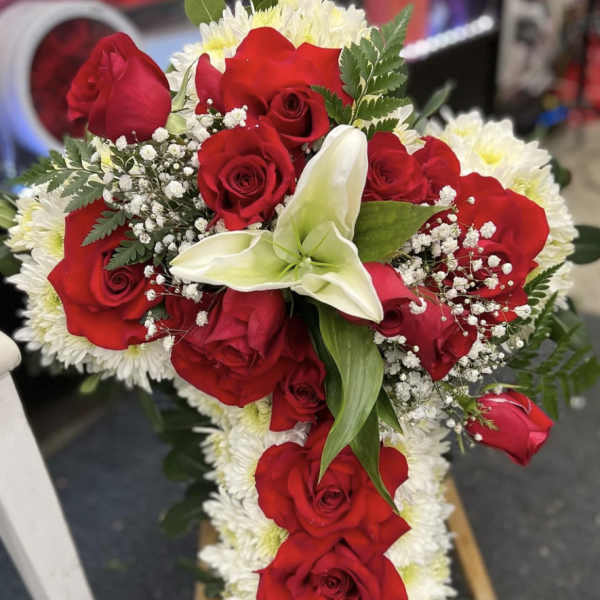 Cross-shaped floral arrangement with red roses and white lilies