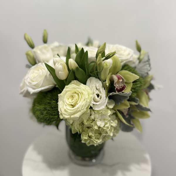 White and pale green floral arrangement in a glass vase