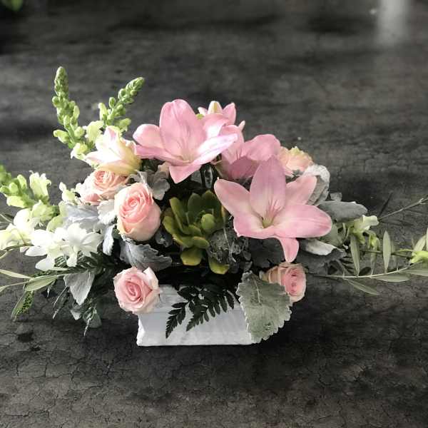Pink and white floral arrangement in a white rectangular container
