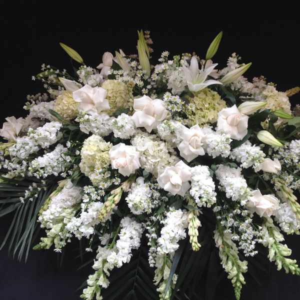 Large white funeral spray with lilies, roses, and clustered white blooms