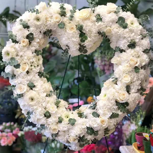 Heart-shaped white floral wreath with roses and greenery