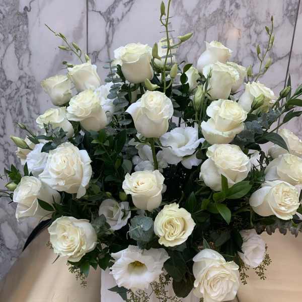 White rose arrangement in a white vase with eucalyptus accents