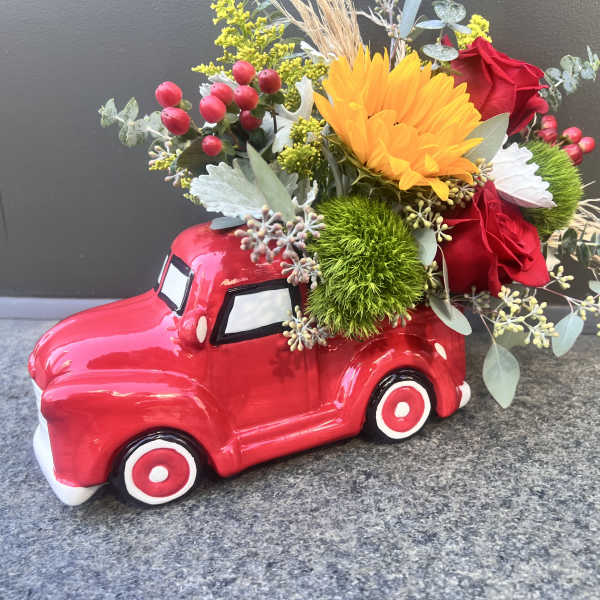 Red truck planter filled with mixed flowers and greenery