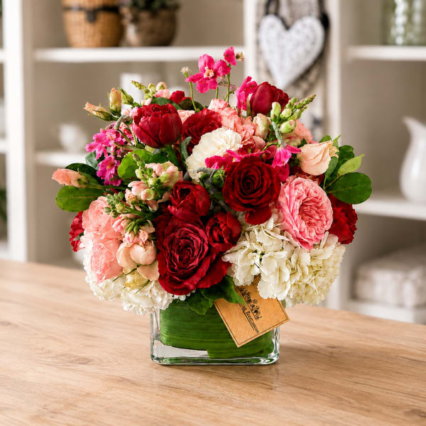 Red, pink, and white bouquet in a square glass vase