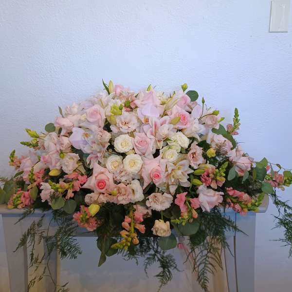 Large pastel floral arrangement with pink and white blooms on a table