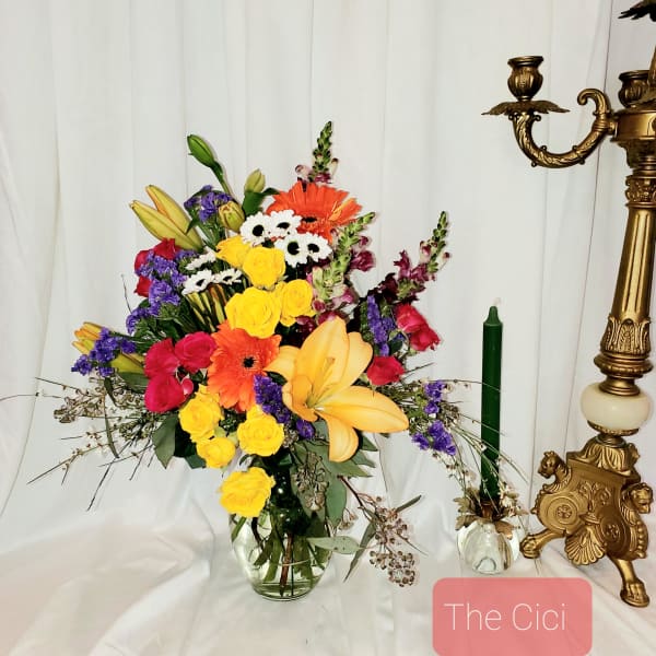 Colorful mixed bouquet in a clear glass vase with lilies and roses