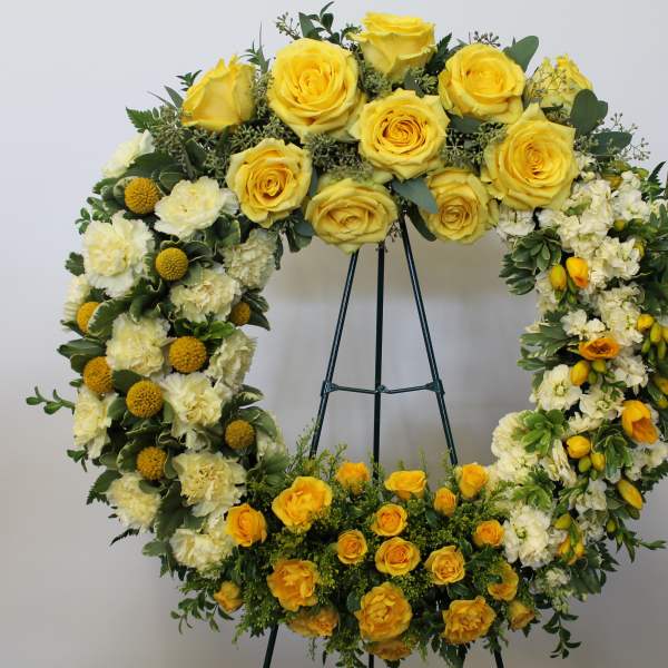 Yellow and white floral wreath on a stand