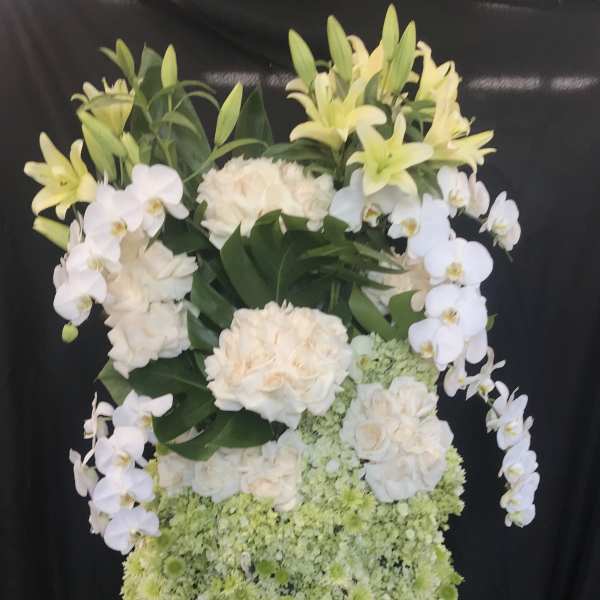 Tall floral arrangement with white orchids, lilies, roses, and green blooms