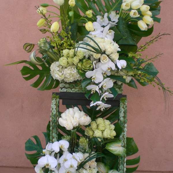 Tall floral arrangement with white orchids, roses, and tropical leaves