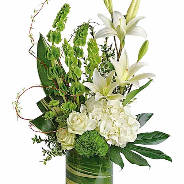 White lilies and roses in a green glass vase with green accents