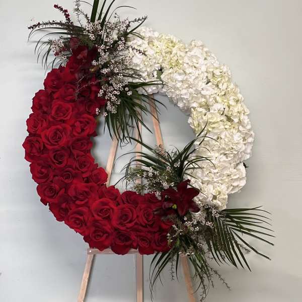 Heart-shaped floral wreath of red roses and white hydrangeas on an easel