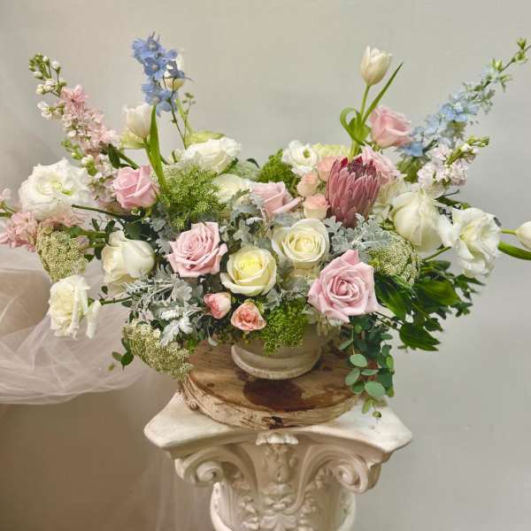 Pastel floral arrangement with roses, tulips, and delphinium in a low bowl