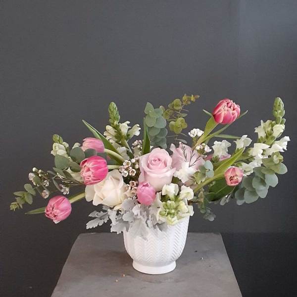 Pink and white flowers arranged in a white vase.