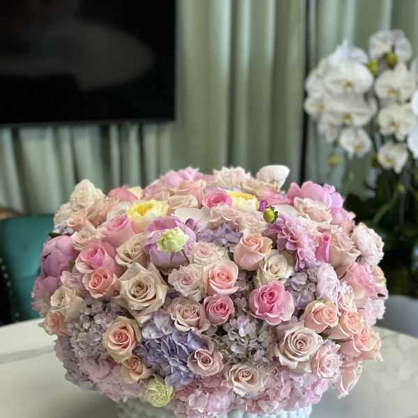 Large pastel bouquet of roses and hydrangeas in a white textured vase