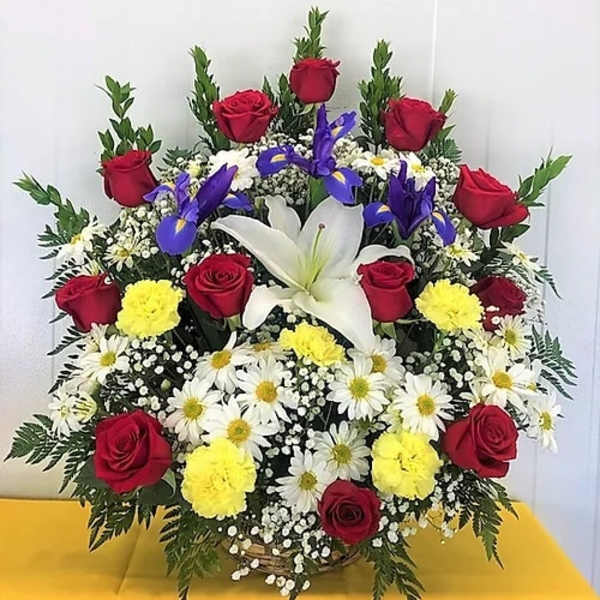 Large mixed flower arrangement with red roses, white lilies, and daisies