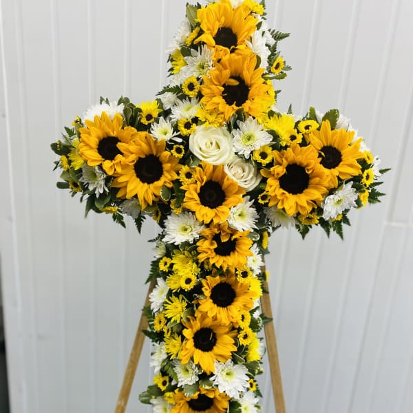 Cross-shaped floral spray with sunflowers and white daisies on an easel