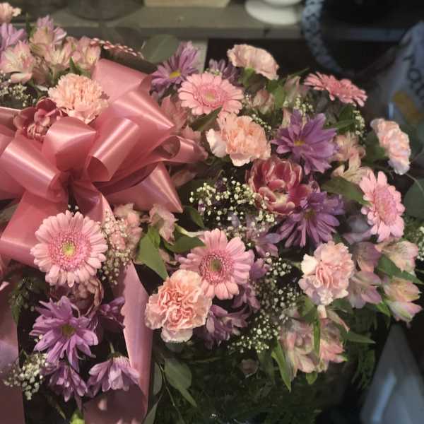 Pink and purple mixed flower arrangement with a large pink bow