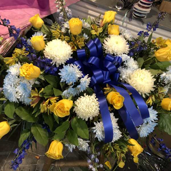 Yellow roses and white chrysanthemums arranged with a blue ribbon bow