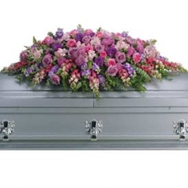 Pink and purple floral casket spray on a gray casket