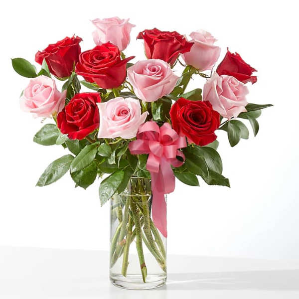 Bouquet of red and pink roses in a clear glass vase with a pink ribbon