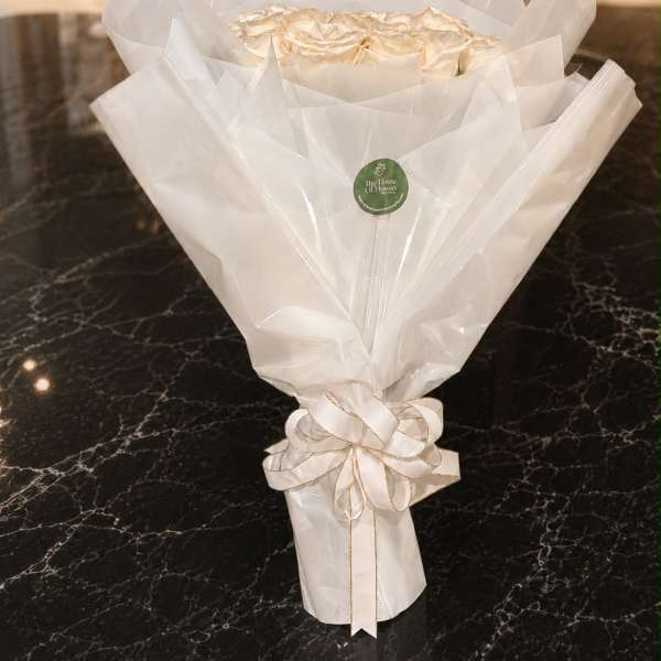 Bouquet of cream roses wrapped in white paper with a ribbon