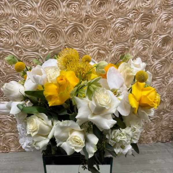 White and yellow floral arrangement in a square vase