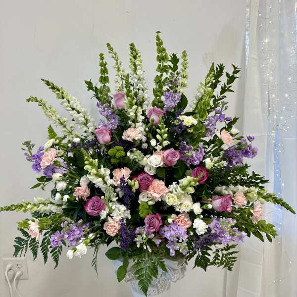 Large pastel floral arrangement in a white pedestal vase