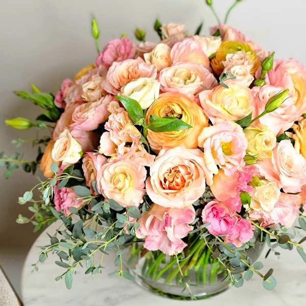 Bouquet of blush and peach roses in a glass vase