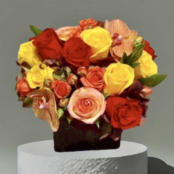 Bouquet of red, yellow, and peach roses in a dark container