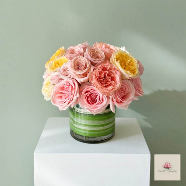 Pink and yellow roses arranged in a striped glass vase