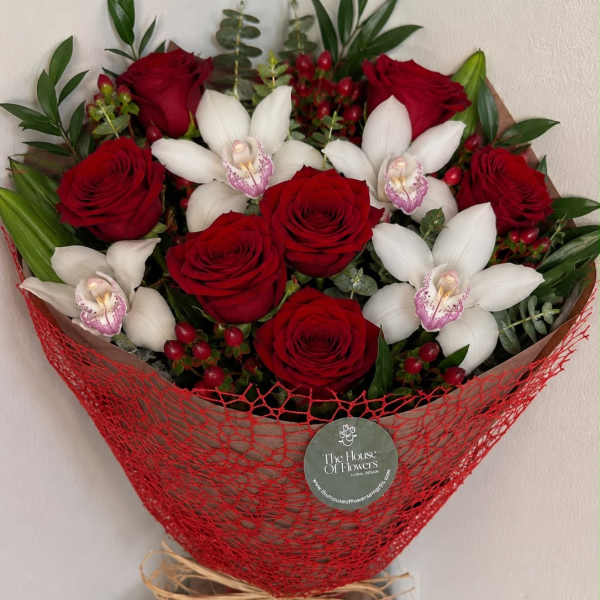 Bouquet of red roses and white orchids wrapped in red mesh