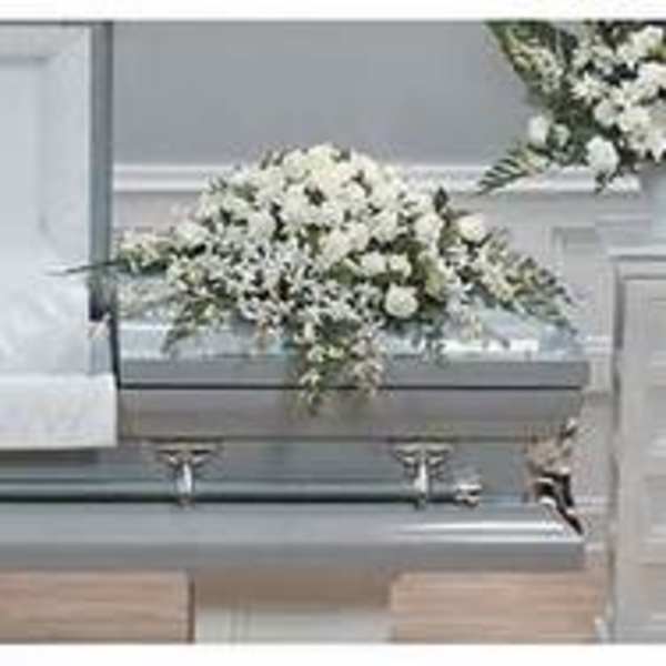 White floral casket spray on a gray casket