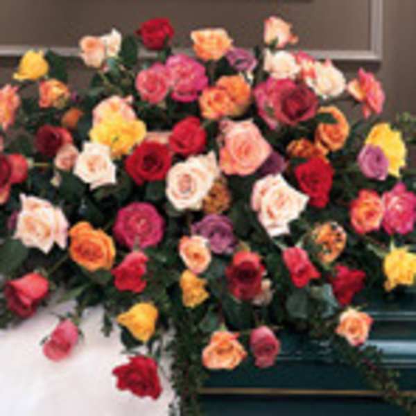 Large casket spray of multicolored roses on a dark casket