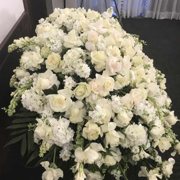 Large white floral casket spray with roses and orchids