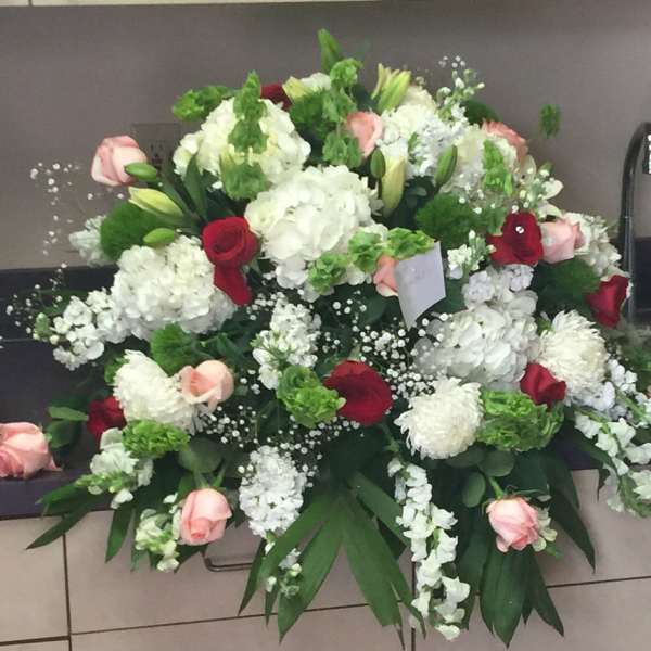 Large floral arrangement with white, pink, and red blooms in a container