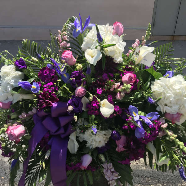 Large floral spray with white, pink, and purple flowers and a purple ribbon